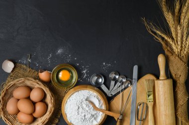 Ekmek unu ve taze yumurta ve aksesuar fırını siyah masada, ev yapımı fırın konseptine hazır olun.