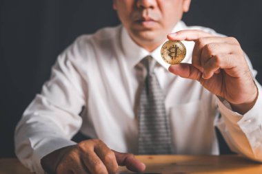 İşadamı, Altın Bitcoin 'i siyah arka planda tutuyor. İnternet bankacılığı ve uluslararası ağ ödemeleri için elektronik sanal para,