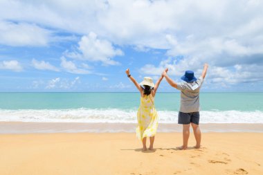 Mutlu çocuklar ellerini kaldırarak geri döndüler Phuket, Tayland 'da bir plajda. İki çekici çocuk deniz kıyısında tatilin tadını çıkarıyor..