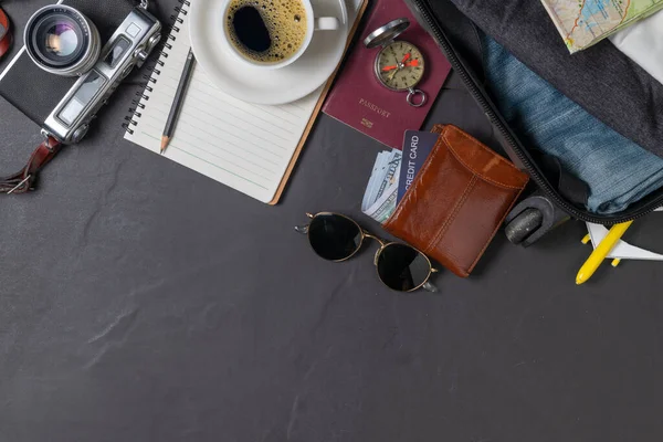 Prepare a suitcase,  vintage camera,  notebook, passport, map and hot coffee on the black tiled floor and copy space. travel concept