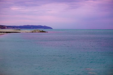 Mor gökyüzünün arka planındaki deniz
