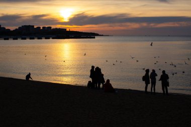Gün batımında denizde insan siluetleri
