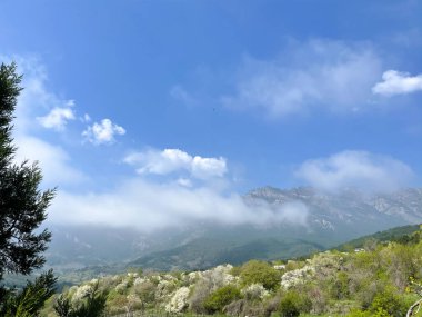 Mavi gökyüzünde bulutlu dağ manzarası