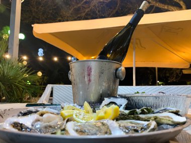 İstiridyelerin arka planında buz kovasında bir şişe şarap.