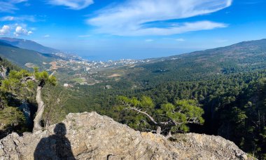 Yüksek bir dağdan panoramik manzaralı taşın üzerindeki bir adamın gölgesi.