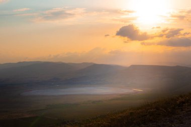 Güneş ışınları dağlarda bir gölü aydınlatıyor.