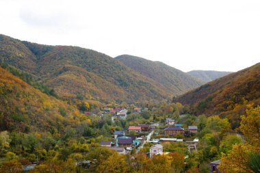 Sonbahar ormanlarıyla çevrili dağlarda bir köy.