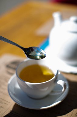 Tepesinde çay kaşığı olan beyaz bir fincan çay.