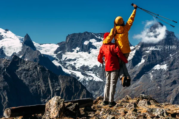 若いカップルは山の中でノルディックウォーキング リアビューを行う アクティブなカップルがハイキングに従事しています 若いカップルが追跡に従事している トレッキングとノルディックウォーキング ハイキングだ スペースのコピー — ストック写真