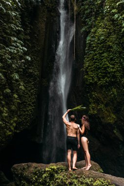 Şelalede turistler, dikiz manzarası. Güzel bir şelalede mutlu bir çift. Bali 'de tatilde olan bir çift. Balayı gezisi. Bali adasında bir tatil. Bali 'de turistler. Boşluğu kopyala