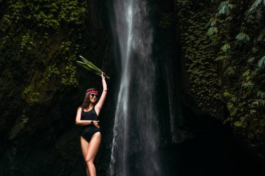 Şelalede gülümseyen güzel bir kızın portresi. Şelalede yeşil yapraklı bir kadının portresi. Endonezya 'da, Bali adasında doğanın arka planında güzel bir kadın..