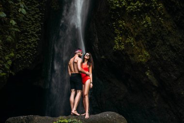 Endonezya 'da bir şelalede güzel bir çift. Balayı gezisi. Bali adasında mutlu bir çift. Güzel bir çift dünyayı gezer. Endonezya 'ya seyahat. Tatildeki mutlu çift. Boşluğu kopyala.
