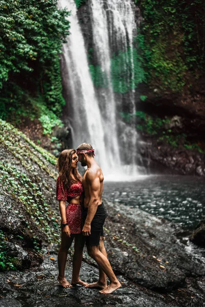 A couple in love on a waterfall. Honeymoon trip. Happy couple on the island of Bali. Beautiful couple travels the world. Travel to Indonesia. Happy couple on vacation.  Wedding trip. Copy space