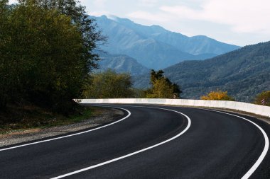 Asfalt yolu. Dağların arkasındaki Paved Yolu. Kafkasya 'daki güzel dağların arka planında. Ülkenin peyzajı. Arabayla güzel yerlerde dolaşmak. Boşluğu kopyala