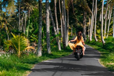 Birbirine aşık bir çift palmiye ağaçlarının arasında scooter kullanıyor. Mutlu çift Sri Lanka 'da tatilde. Çift dünyayı geziyor. Asya 'da tatil. Sri Lanka 'da motosikletle seyahat etmek. Sri Lanka 'da Tatil