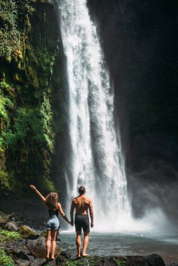 Şelaledeki çift, dikiz manzaralı. Bali 'de tatilde olan bir çift. Balayı gezisi. Aşık bir çift dünyayı gezer. Bali adasında bir tatil. Bali 'de turistler. Boşluğu kopyala