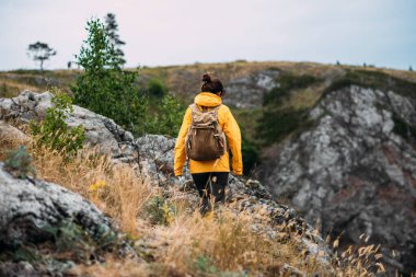 Dağ yolcusu, dikiz aynası. Dağ sporları. Dağ turizmi. Yürüyüş turu. Dağlara yolculuk. Sırt çantalı, dağların arka planında gezen kadın, dikiz manzaralı. Boşluğu kopyala