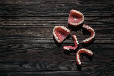 Koyu bir arka planda takma dişler. Takma dişlerin yakın plan çekimi. Çenenin tamamen çıkarılabilir plastik protezi. Protez dişçilik. Takma diş. Plastik protezlere yakın çekim. Siyah arkaplanda dişler