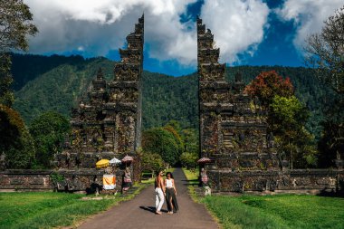 Traveling couple in Bali. Happy couple vacationing in Asian countries. Couple at the Bali gate. A man and a woman traveling on the island of Bali Indonesia. The couple is traveling in Indonesia clipart