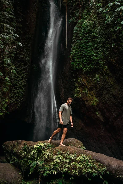 A man at the waterfall. A person travels around the world. The man at the waterfall. Travel to Bali, Indonesia. A person travels through picturesque places. A lone traveler. Copy space