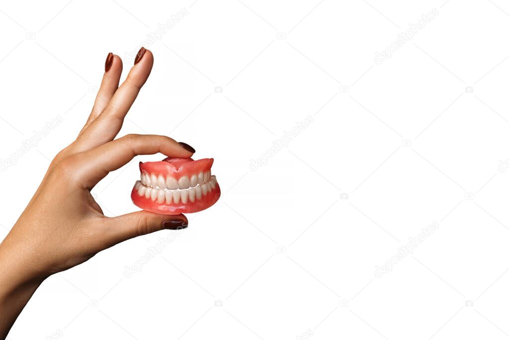 The dentist is holding dentures in his hands. Dental prosthesis in the hands of the doctor close-up. Front view of a complete denture on a white background. Dentistry conceptual photo. False teeth