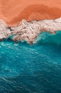 Mavi denizi ve dikey manzarası olan güzel kumlu sahil. Tropikal mavi okyanus sahili Nusa Penida Bali Endonezya 'nın insansız hava aracı görüntüsü. Güzel dalgaları olan ıssız kumlu bir sahil. Kumsal duvar kâğıdı. Boşluğu kopyala