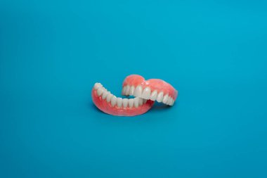 Çenenin tamamen çıkarılabilir plastik protezi. Mavi arka planda takma dişler. İki akrilik takma diş. Üst ve alt çeneler ve takma dişler. Takma dişler ya da takma dişler, yakın plan. Boşluğu kopyala