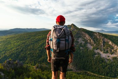 Dağların arka planında bir gezgin. Sırt çantalı bir turist dağın tepesinde duruyor. Gün batımında sırtında sırt çantası olan bir adam, dikiz aynasından. Ev turizmi. Boşluğu kopyala