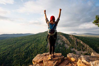 Sırt çantalı bir kadın, elleri havada, dikiz aynasıyla dağların arka planında duruyor. Dağlarda bir adam ellerini kaldırıyor. Dağların arka planında bir adam. Boşluğu kopyala