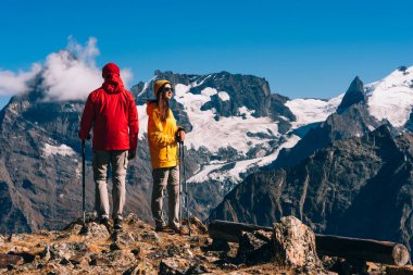 Genç bir çift dağlarda, dikiz aynasından İskandinav yürüyüşü yapıyor. Yürüyüş 'te aktif bir çift var. Genç bir çift iz sürmekle meşgul. Seyahat ve İskandinav yürüyüşü. Yürüyüş. Boşluğu kopyala