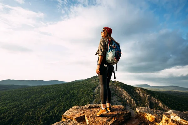 A woman meets the sunset in the mountains. Man travels in the mountains. Mountain tourism. The journey to the mountains. Man on the background of a beautiful evening landscape. Copy space