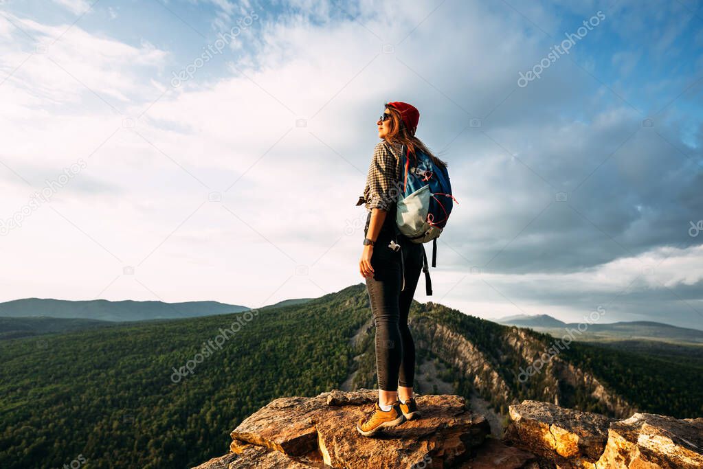 A woman meets the sunset in the mountains. Man travels in the mountains. Mountain tourism. The journey to the mountains. Man on the background of a beautiful evening landscape. Copy space