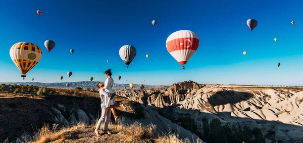 幸せな若いカップルは カッパドキア トルコ パノラマの日の出の間に気球を楽しんでいます トルコで休暇中の男と女は風船を見る 新婚旅行だ トルコの観光地への旅行 — ストック写真