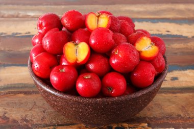 Red acerola - malpighia glabra, tropical fruit  in bowl on table clipart