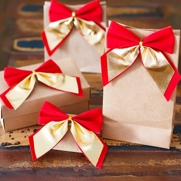 Paquete de papel de regalo de Navidad con lazo rojo dorado —  Fotos de Stock