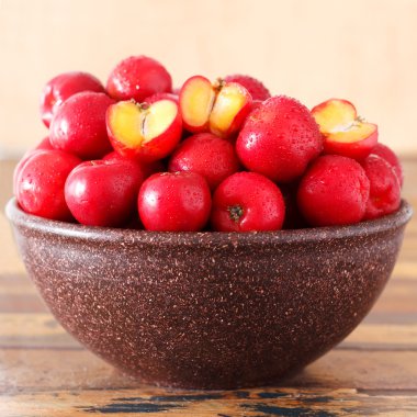 Red acerola (malpighia glabra), tropical fruit  in brown bowl clipart