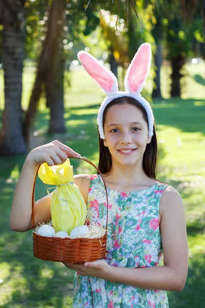 Smiling cute teen girl with rabbit ears holding chocolate eggs — Stock Photo, Image