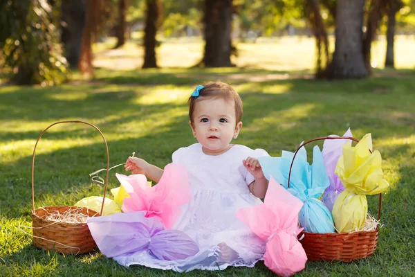 Cute  baby girl in white dress with Easter chocolate eggs in par — Stock Photo, Image