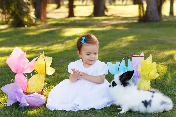 Smiling baby girl looking at rabbit with Easter chocolate eggs — Stock Photo, Image