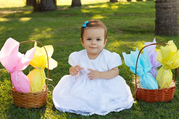 Cute smiling baby girl with basket with chocolate eggs for Easte — Stock Photo, Image