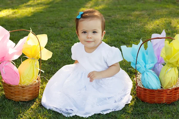 Cute smiling baby girl on green grass with Easter chocolate eggs — Stock Photo, Image