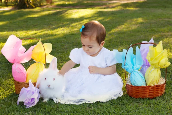 Cute dziewczynka dziecko w białej sukni dotykając królik, Wielkanoc cho — Zdjęcie stockowe