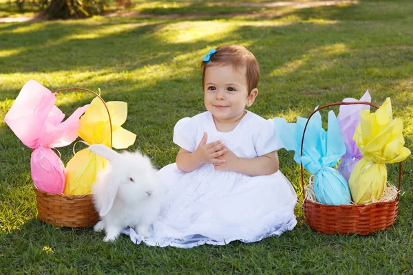 Szczęśliwy uśmiechający się dziewczynka z białego królika i czekoladowe pisanki — Zdjęcie stockowe