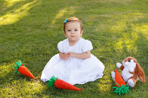 Cute little baby girl in white dress with toy rabbit and carrot — Stock Photo, Image