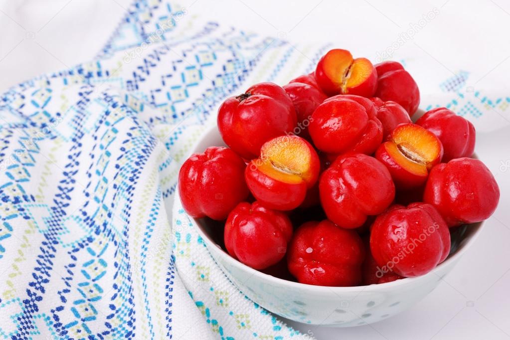 Malpighia glabra (red acerola), tropical fruit in bowl 