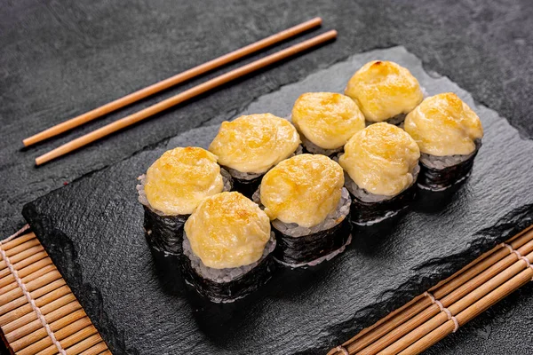 Baked roll with shrimp and masago caviar cap. Traditional sushi restaurant dish, menu item. National japanese cuisine appetizer. Delicious oriental snack, gourmet seafood on wooden platter closeup