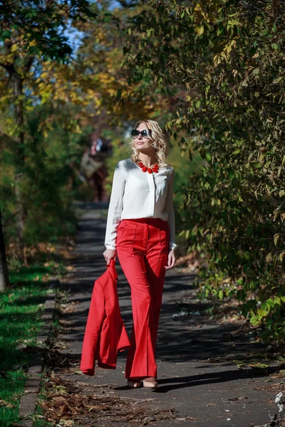 Красивая девушка в красном костюме осенью — стоковое фото