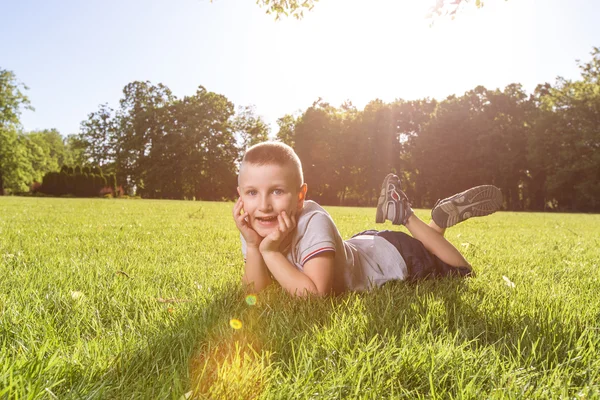 Счастливый мальчик, лежащий на траве — стоковое фото