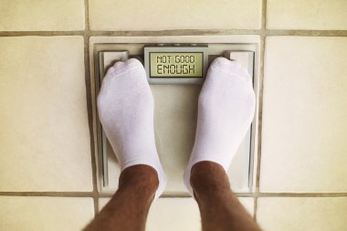 Man's feet on bathroom scale. Diet concept clipart