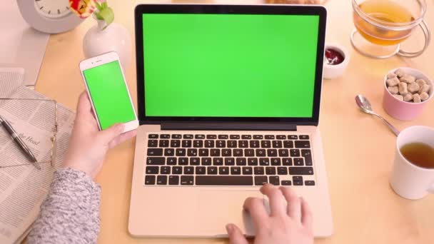 Mujer usando portátil y teléfono pantalla verde maqueta — Vídeos de Stock